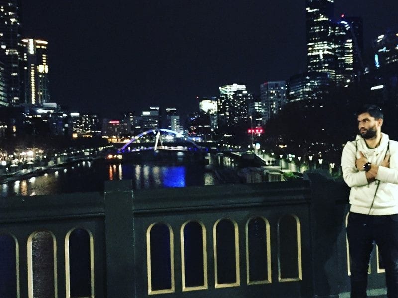 Dani en Australia chico joven en un puente y mirando la ciudad de Melbourne de noche iluminada
